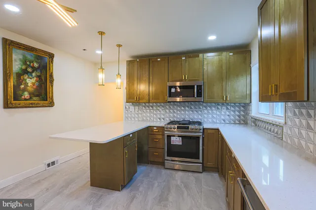 a kitchen with stainless steel appliances kitchen island granite countertop a stove a sink and a microwave