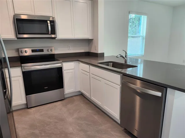 a kitchen with granite countertop white cabinets stainless steel appliances and a sink