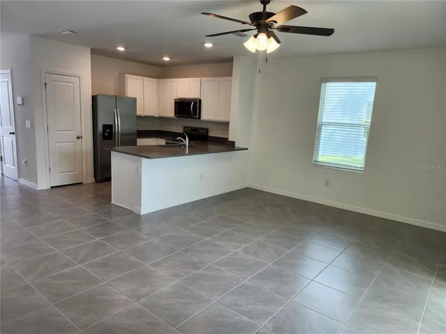 a kitchen with kitchen island granite countertop a stove a sink a refrigerator a counter top space and cabinets