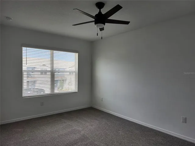 an empty room with a window and a fan