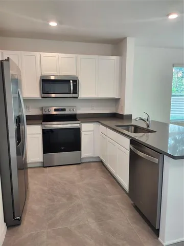 a kitchen with stainless steel appliances granite countertop a sink a stove a microwave a refrigerator a sink and dishwasher