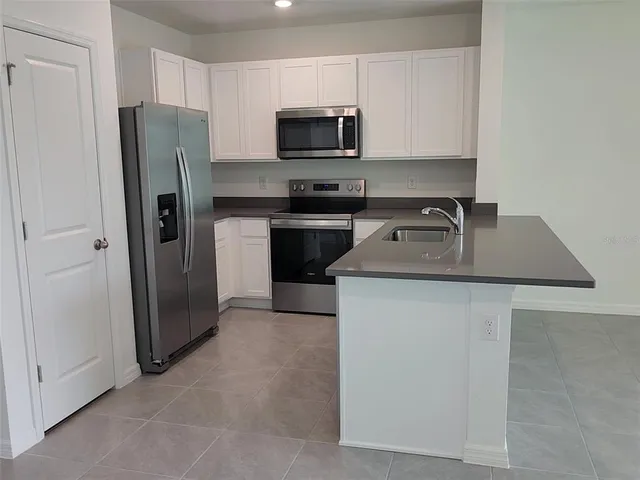 a kitchen with stainless steel appliances granite countertop a refrigerator stove a sink and a microwave