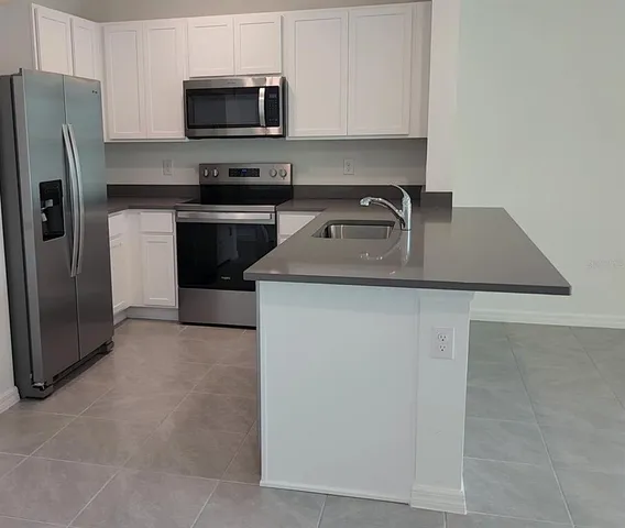 a kitchen with stainless steel appliances granite countertop a stove a refrigerator and a microwave