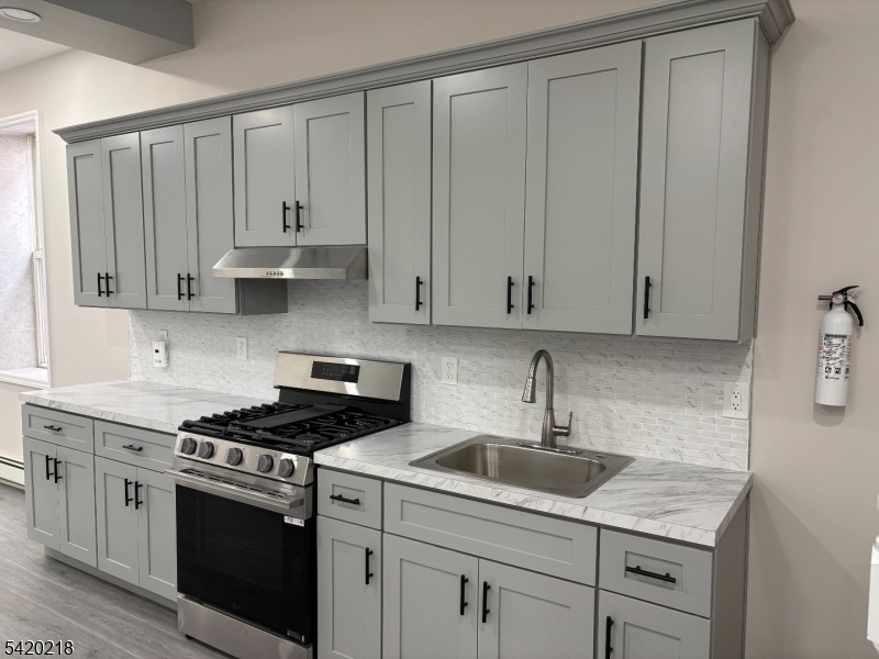 127 Fulton Street Elizabeth Port, NJ 07206 - Photo 2 of 21 a kitchen with granite countertop white cabinets and stainless steel appliances
