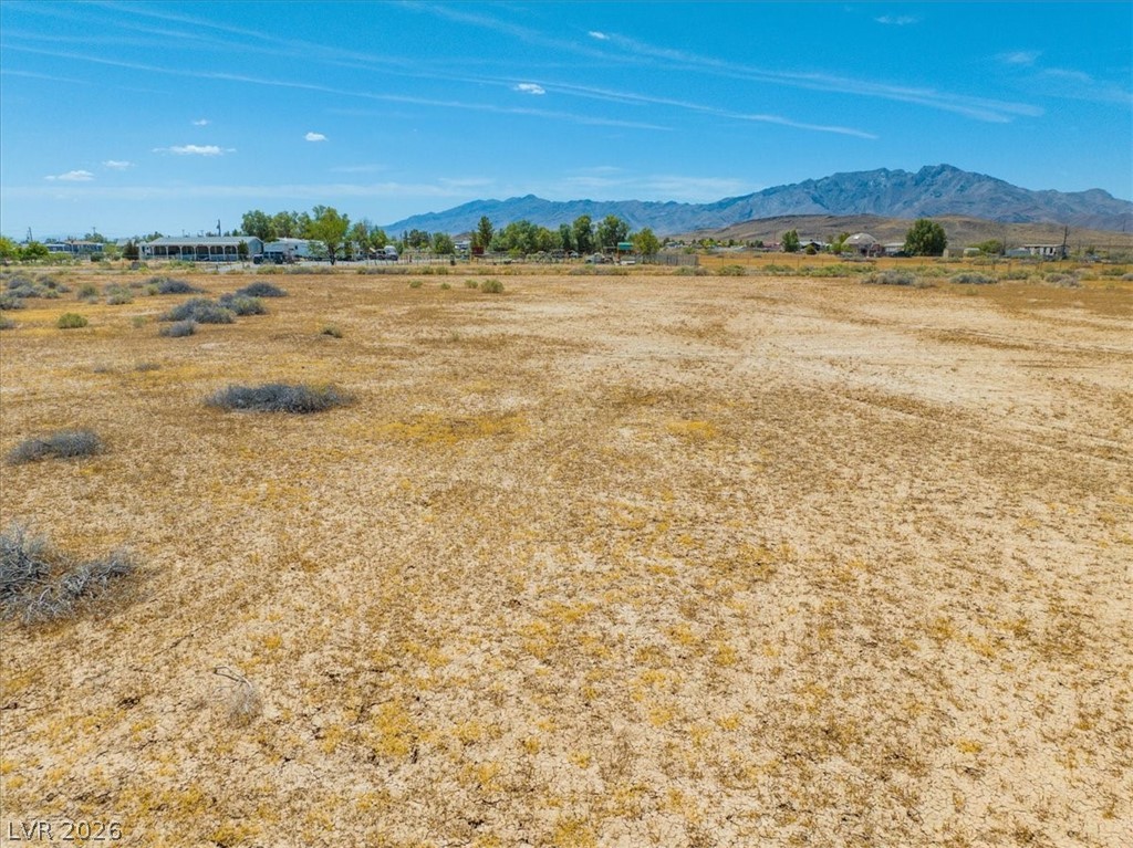 4610 Lawrence Road Pahrump, NV 89048 - Photo 13 of 42 A vast, level lot ready for development, framed by distant mountains under an expansive sky.