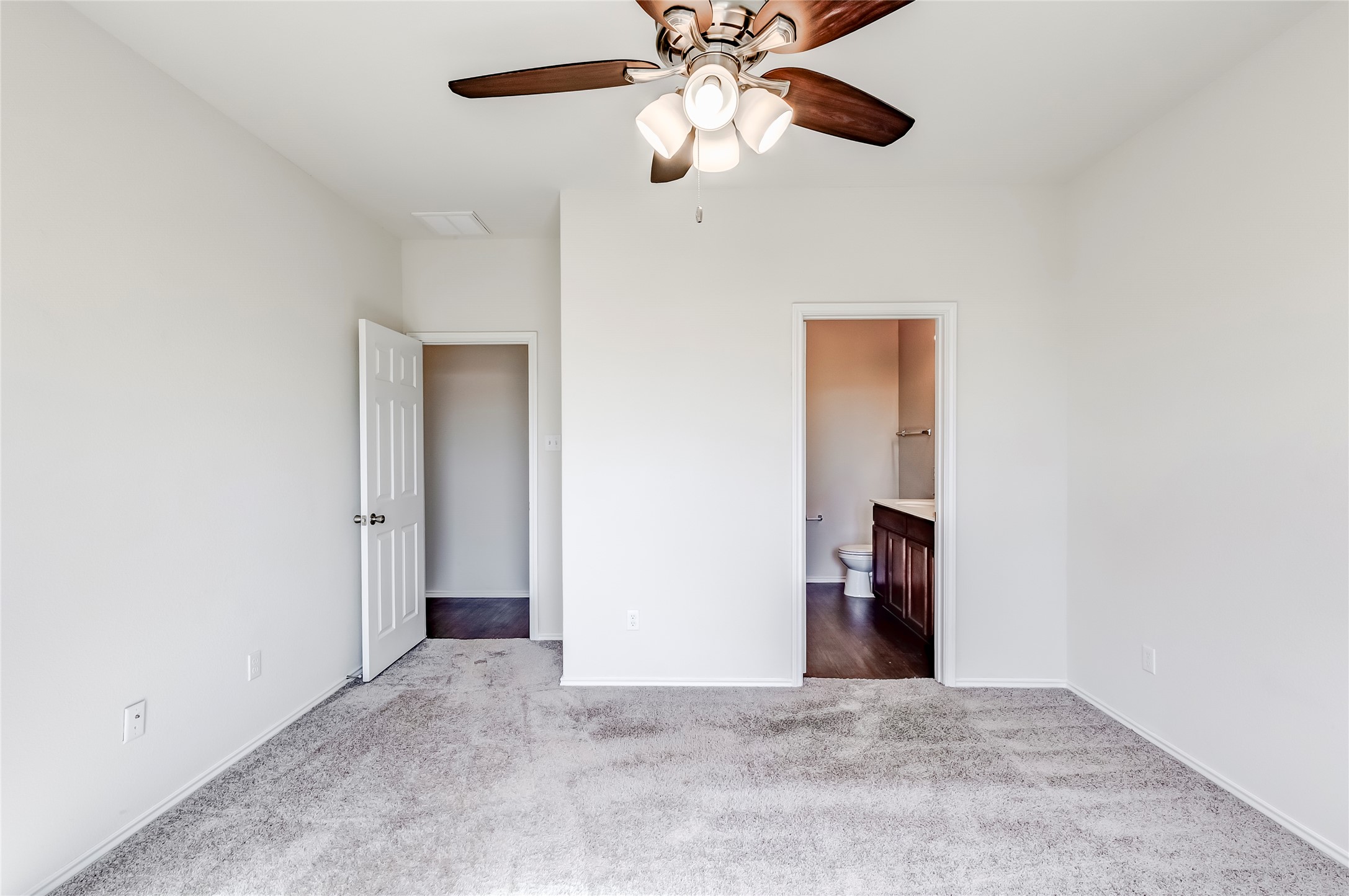 11617 Amber Stream Lane Manor, TX 78653 - Photo 14 of 39 Unfurnished bedroom featuring connected bathroom, dark colored carpet, and ceiling fan