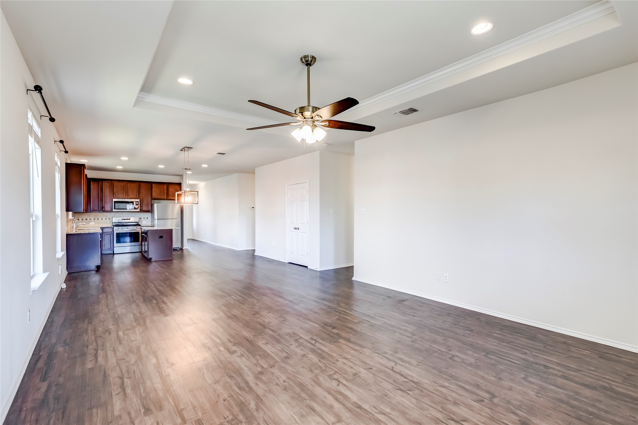 11617 Amber Stream Lane Manor, TX 78653 - Photo 7 of 39 Unfurnished living room featuring recessed lighting, a tray ceiling, a ceiling fan, dark wood finished floors, and ornamental molding