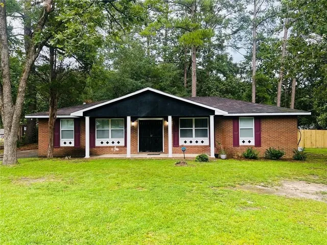 a front view of a house with a yard and trees
