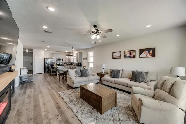 a living room with furniture kitchen view and a chandelier