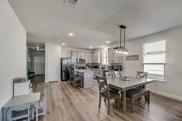 a view of a dining room and livingroom with furniture wooden floor a rug a flat screen tv a painting and a chandelier