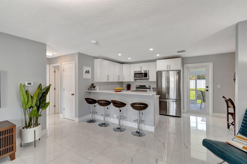 710 Southeast 3rd Avenue Delray Beach, FL 33483 - Photo 4 of 31 a kitchen with stainless steel appliances kitchen island granite countertop a refrigerator and a sink