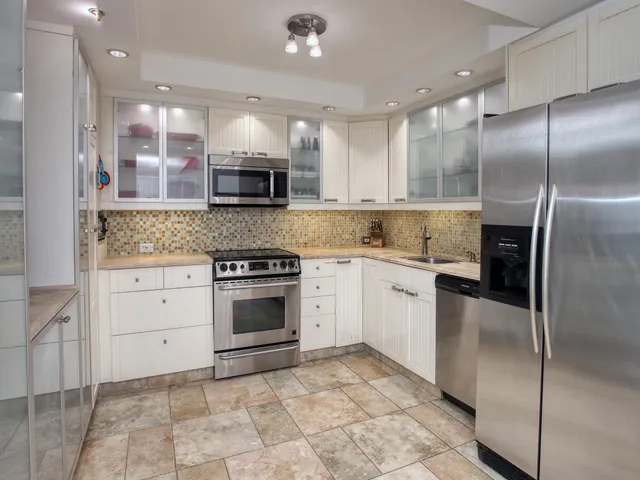 a large kitchen with stainless steel appliances kitchen island granite countertop a stove a sink and a refrigerator
