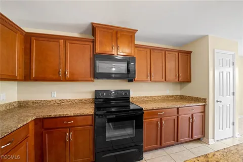 a kitchen with granite countertop a stove top oven microwave and cabinets