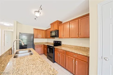 a kitchen with stainless steel appliances granite countertop a sink refrigerator and cabinets