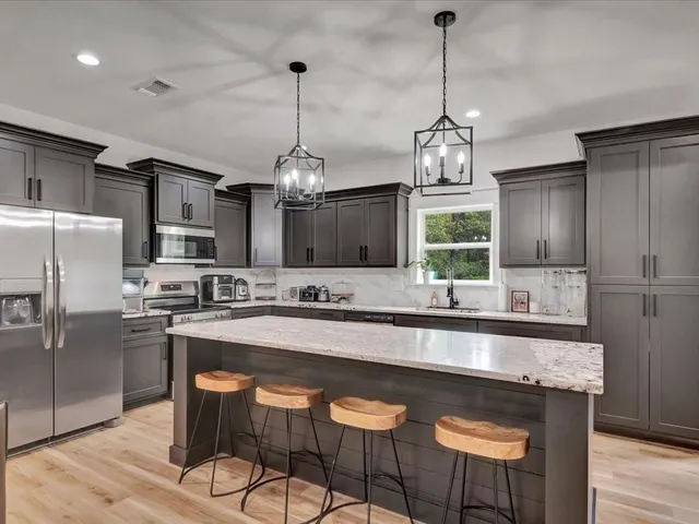 a kitchen with stainless steel appliances granite countertop a sink a stove a refrigerator and island