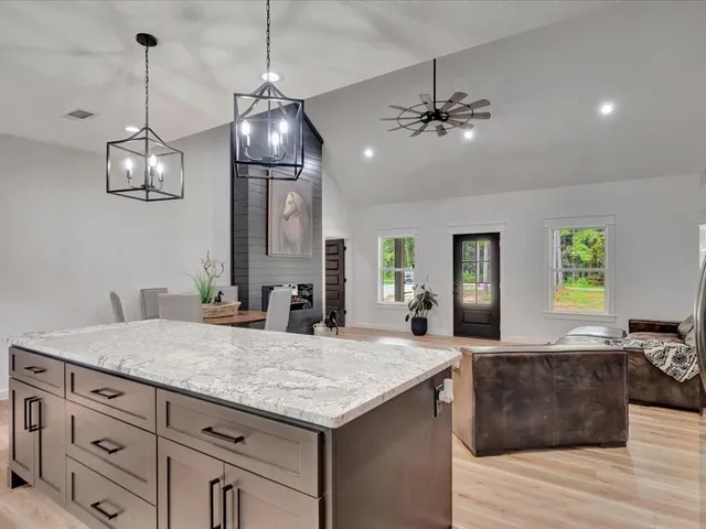 a kitchen with center island chandelier and living room view