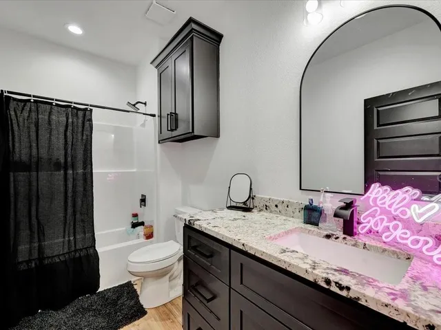 a bathroom with a granite countertop sink a toilet and shower