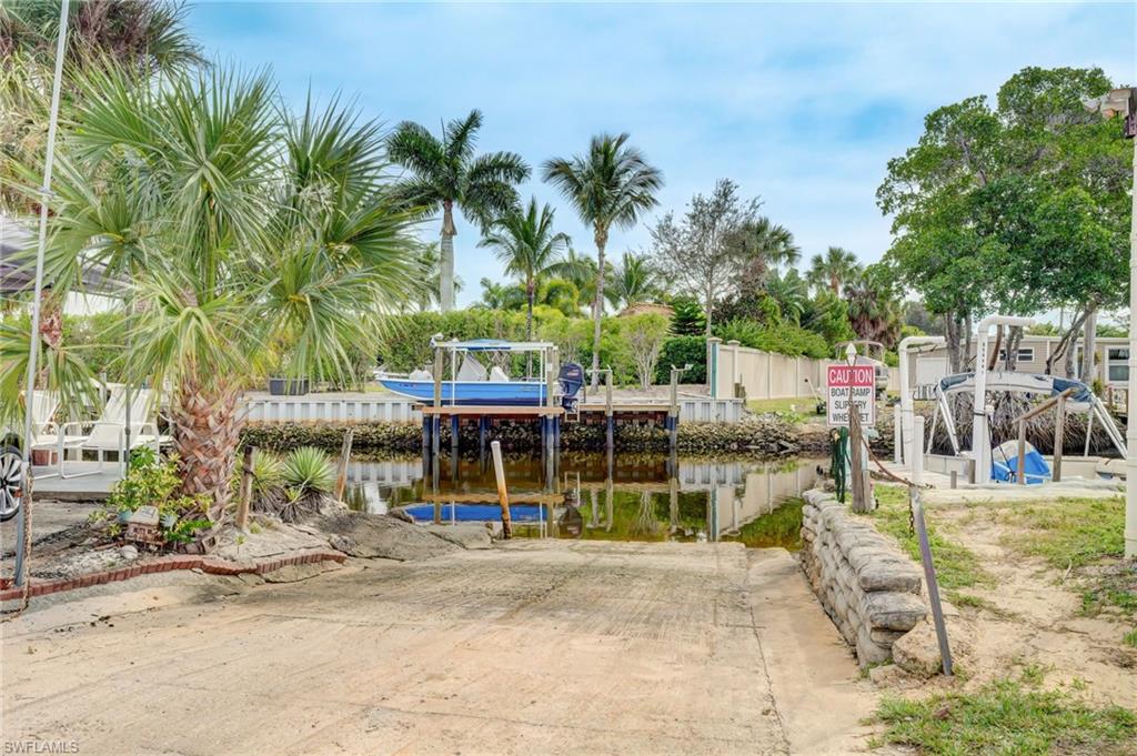 104 Willow Lane, Unit 30 Naples, FL 34114 - Photo 22 of 27 a view of a patio with a table and chairs under an umbrella with large trees