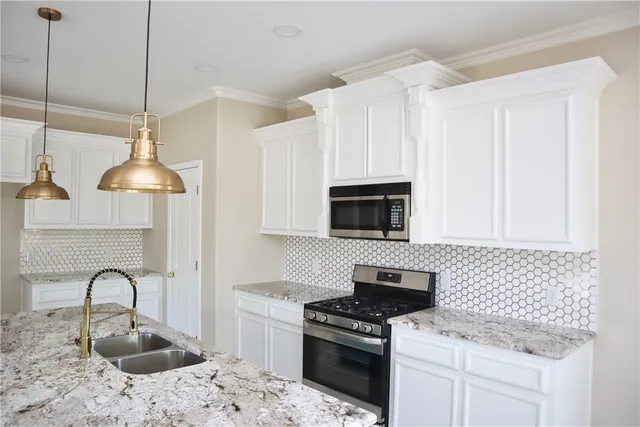 a kitchen with granite countertop a stove a sink and a microwave