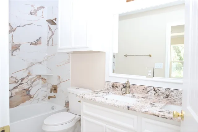 a bathroom with a bathtub sink vanity mirror and toilet
