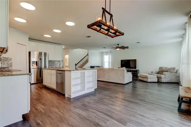 a kitchen with stainless steel appliances granite countertop a sink refrigerator and cabinets