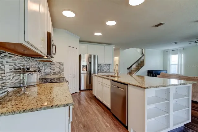 a kitchen with stainless steel appliances a refrigerator and wooden floor