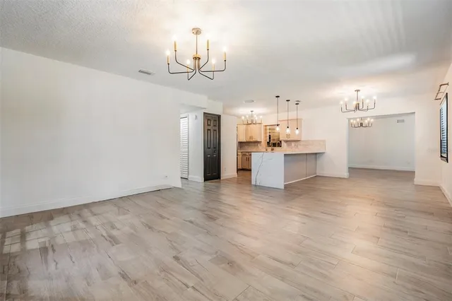 a view of a kitchen with a sink and cabinet wooden floor windows and a chandelier