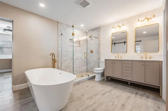 a bathroom with a bathtub shower sink mirror and toilet