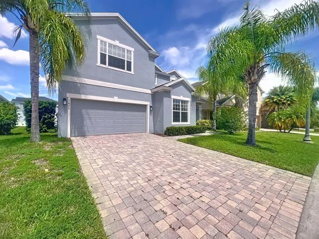a front view of a house with a yard and palm trees