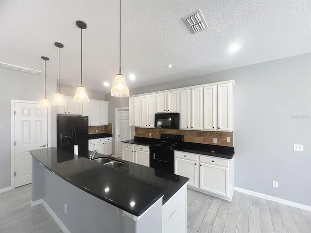 a kitchen with stainless steel appliances granite countertop a sink a stove and a wooden floor