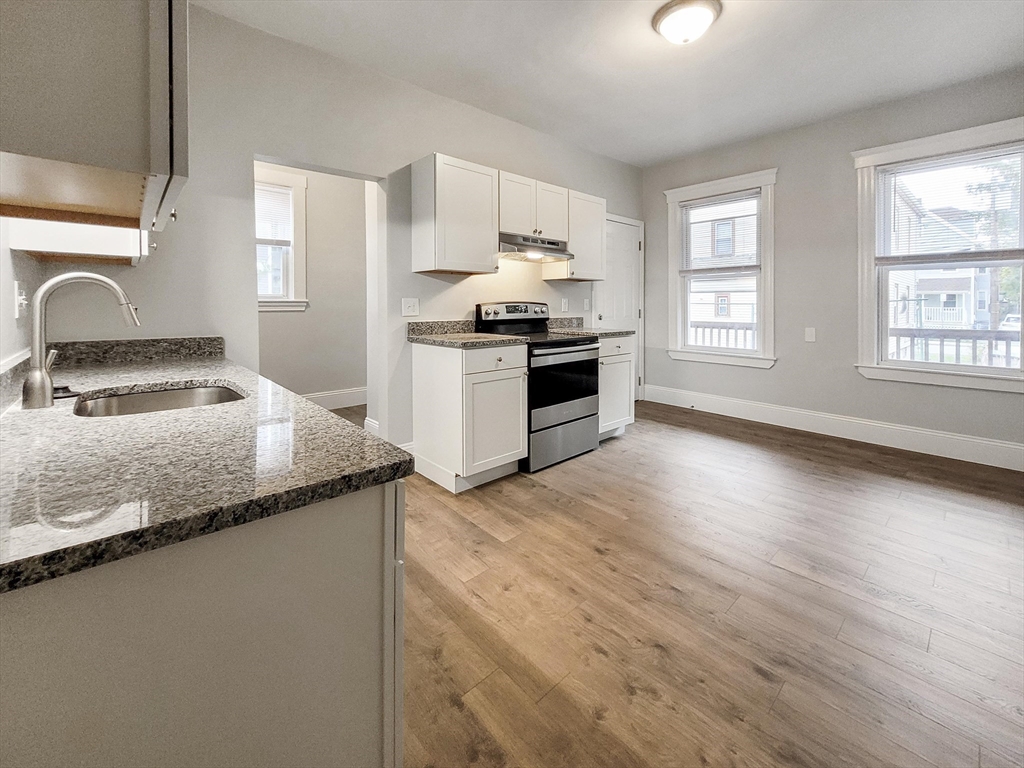 108 Callender Street, Unit 1 Boston, MA 02124 - Photo 2 of 9 a kitchen with granite countertop a sink cabinets and stainless steel appliances