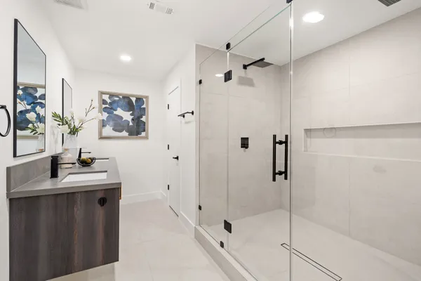 a bathroom with a shower sink vanity and mirror