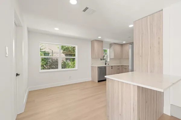 a view of kitchen with stainless steel appliances granite countertop white cabinets and window