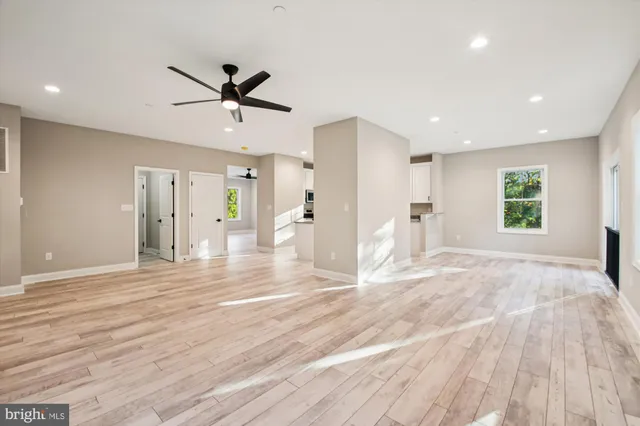 a view of a livingroom with a chandelier fan and wooden floor