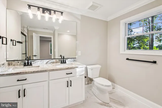 a bathroom with a granite countertop sink mirror a toilet and a window