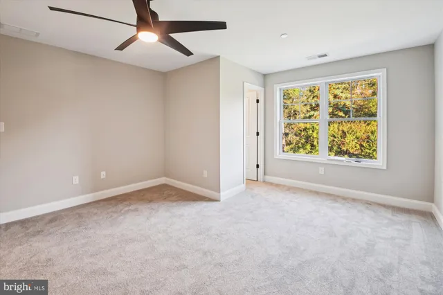 an empty room with a window and a ceiling fan