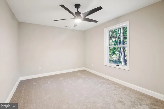 an empty room with a window and a ceiling fan