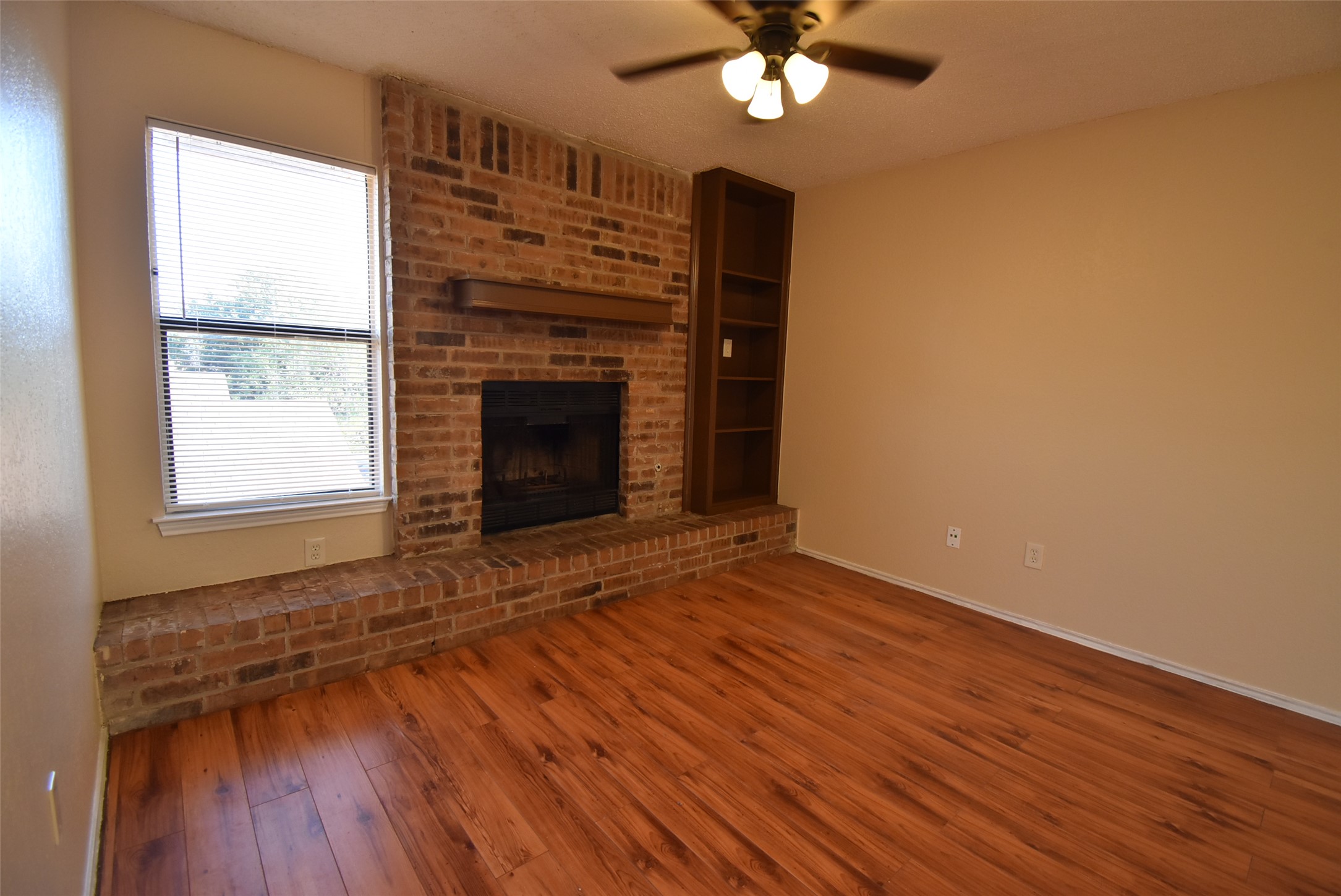1806 Rawhide Loop Round Rock, TX 78681 - Photo 1 of 23 Unfurnished living room with laminate flooring, ceiling fan, brick fireplace and bookshelves
