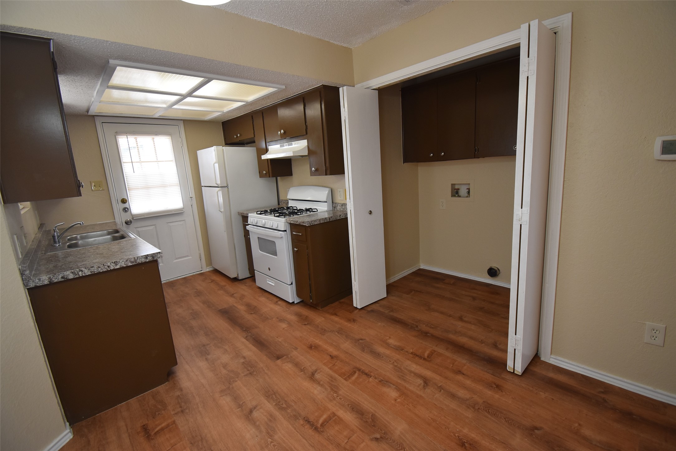 1806 Rawhide Loop Round Rock, TX 78681 - Photo 11 of 23 Kitchen featuring white appliances, dark wood finish cabinets, laminate floors, textured ceiling, and light countertops