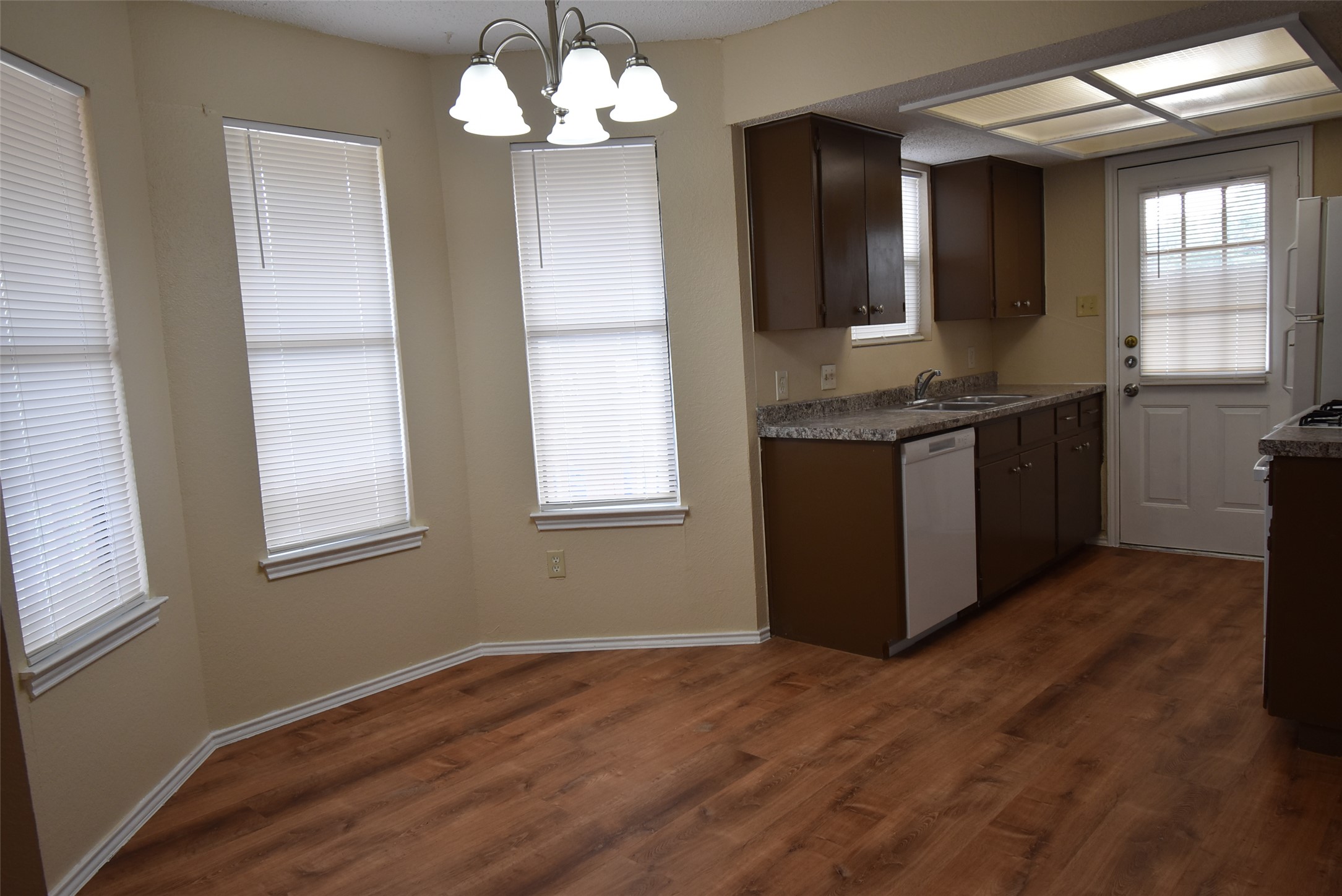 1806 Rawhide Loop Round Rock, TX 78681 - Photo 6 of 23 Kitchen with suspended lighting, dark wood finish cabinetry, freestanding refrigerator, dishwasher, and laminate floors