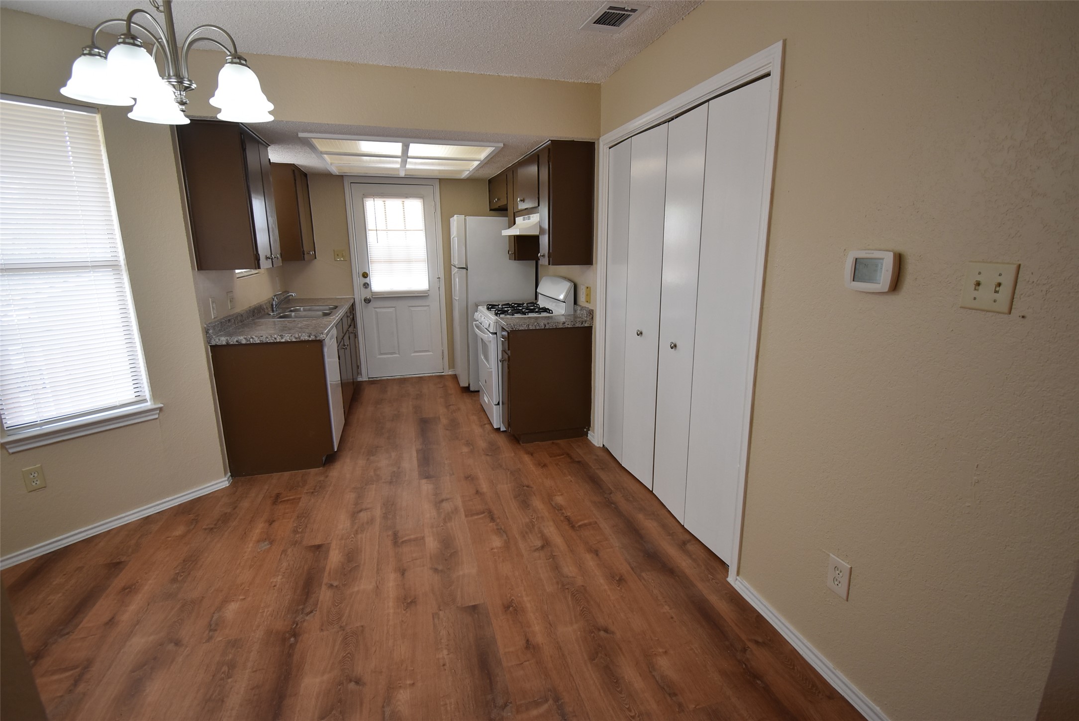 1806 Rawhide Loop Round Rock, TX 78681 - Photo 7 of 23 Kitchen featuring gas range gas stove, dark wood finish cabinetry, light countertops, laminate flooring, and hanging lights