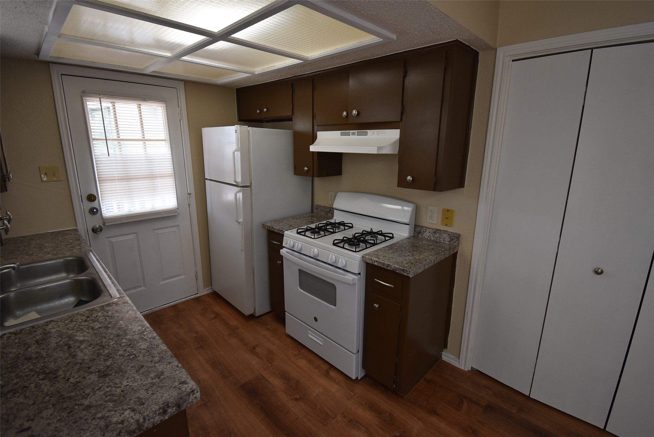 1806 Rawhide Loop Round Rock, TX 78681 - Photo 9 of 23 Kitchen featuring white range with gas stovetop, dark wood finish cabinetry, laminate floors, and dark countertops