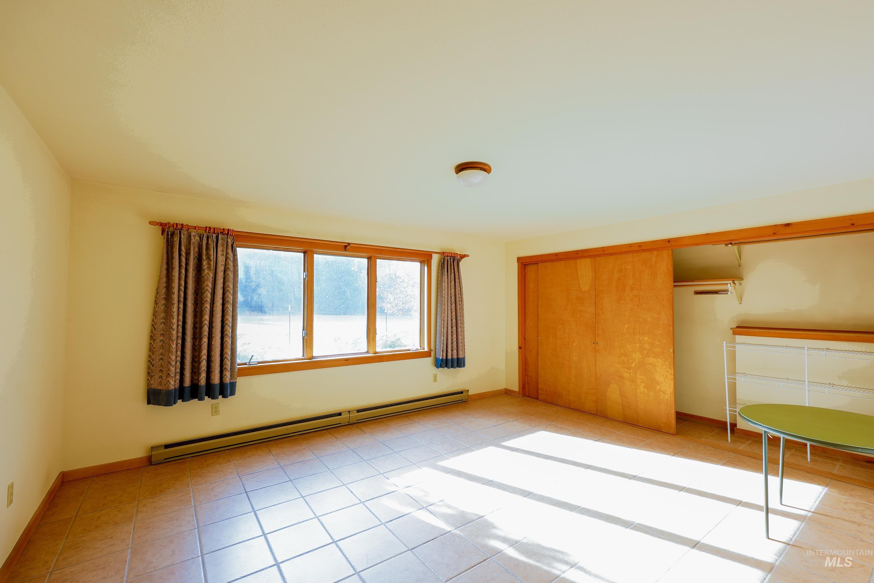 1021 Claypit Road Troy, ID 83871 - Photo 24 of 44 Unfurnished bedroom with baseboard heating, a closet, and light tile patterned flooring