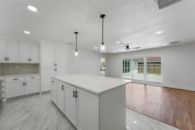 a large kitchen with kitchen island a stove a sink a center island and wooden floor