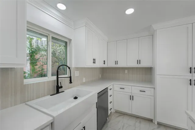 a kitchen with white cabinets and sink