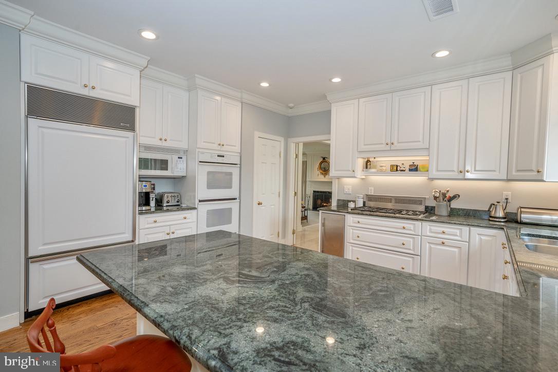 1201 Denbigh Lane Wayne, PA 19087 - Photo 13 of 54 a kitchen with stainless steel appliances granite countertop a stove top oven a sink and white cabinets