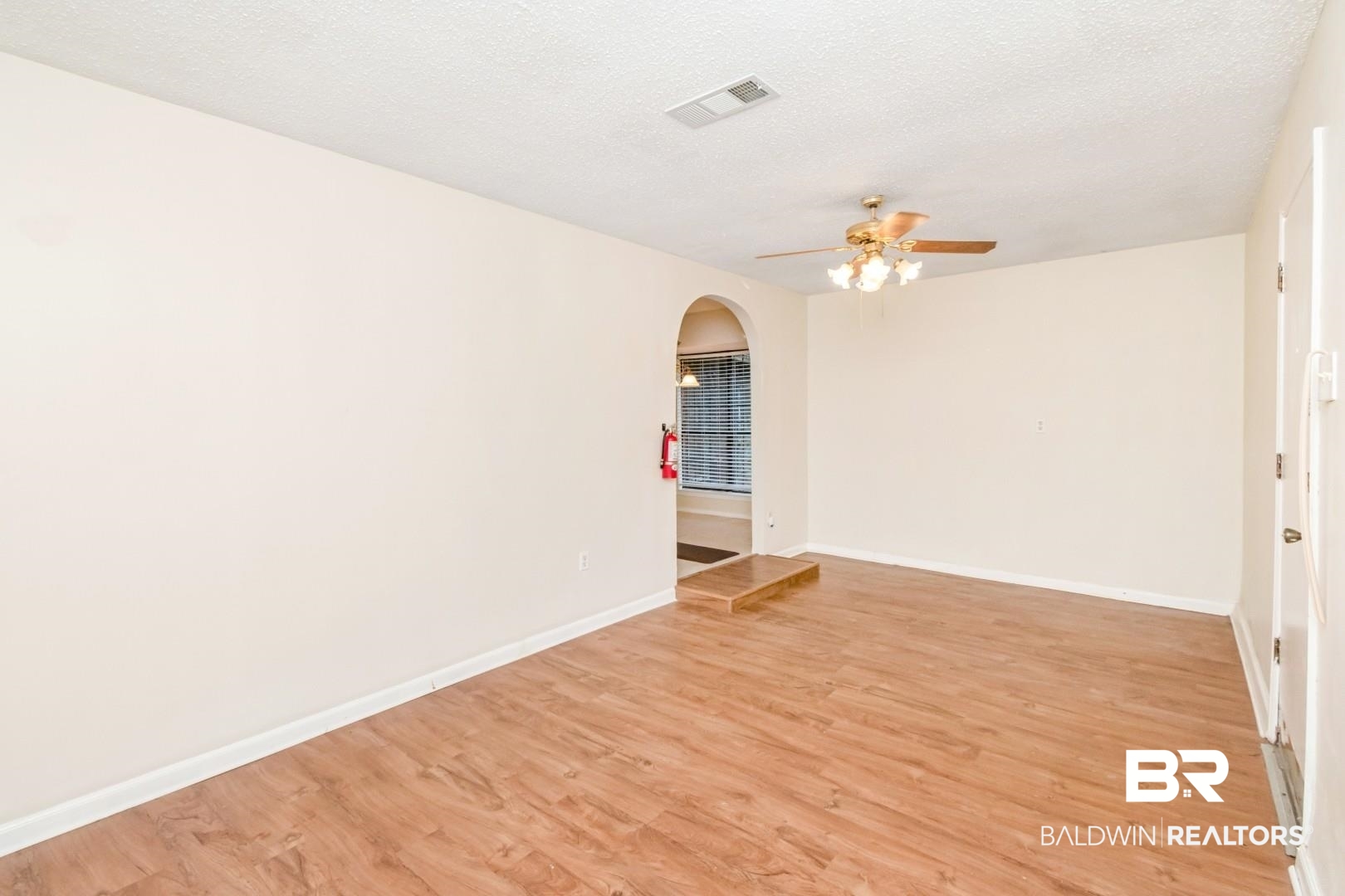 5812 Fern Valley Road Mobile, AL 36609 - Photo 12 of 32 Spacious interior room featuring wood-finish flooring, a ceiling fan with integrated lighting, and an arched doorway