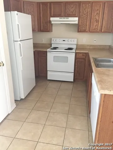 a kitchen with a stove top oven and refrigerator