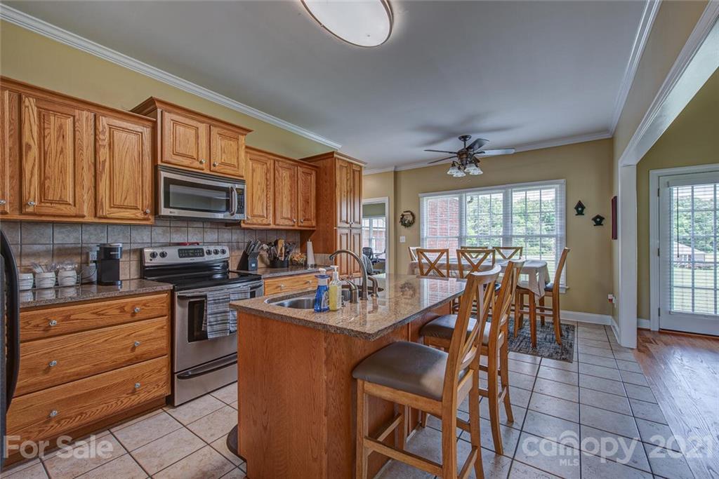 936 Ferguson Ridge Road Gastonia, NC 28052 - Photo 10 of 30 a kitchen with stainless steel appliances granite countertop a stove top oven a sink a dining table and chairs with wooden floor