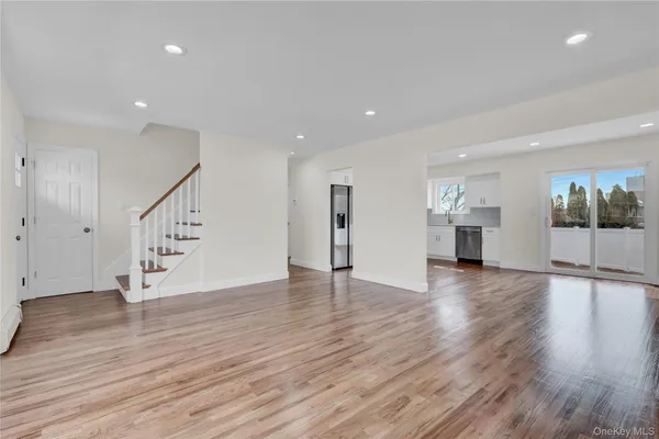 a view of an empty room with wooden floor and windows